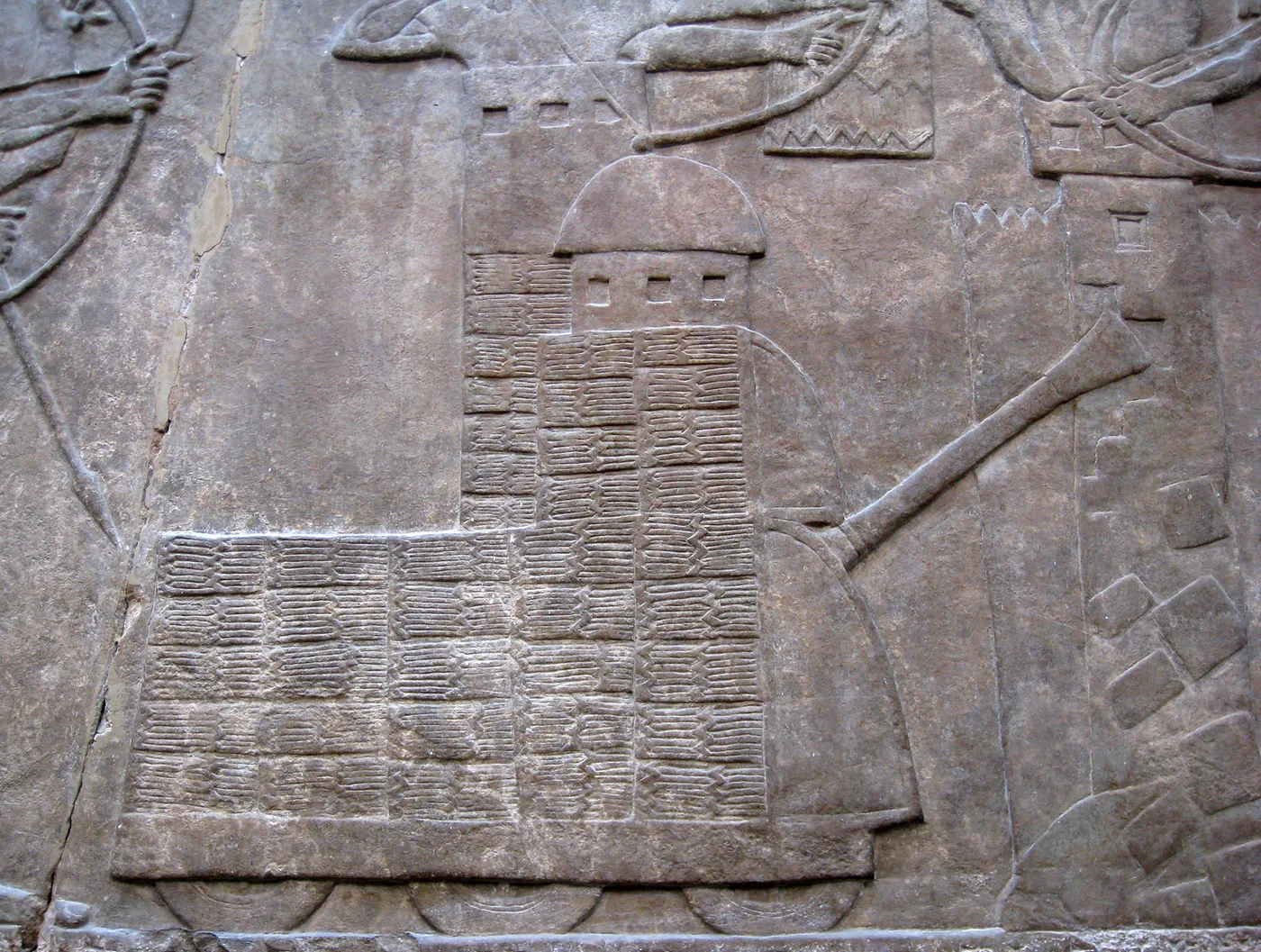 A large wheeled Assyrian battering ram attacks the walls of a besieged city, while archers on both sides exchange arrows (Nimrud, about 865-860 BC; British Museum)